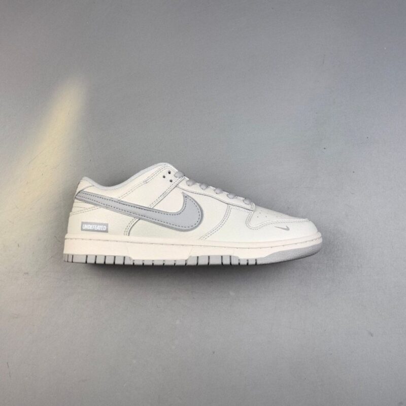 【AT3108】Undefeated x Nike Dunk SB Low Und x ナイキダンクSBロー コラボレーション ホワイトグレー。シューズのベースカラーは白色で、非常に汎用性があります。また、Swooshロゴのディテールパッチはシルバーで作られており、さらにクールに見えます。
