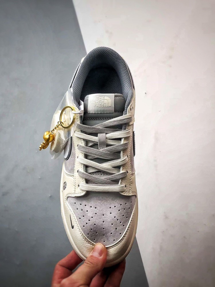 【AT3271】Nike x The North Faceのコラボレーションモデル、グレーと白の組み合わせのローカットシューズ、Nike Dunk Low RetroとThe North Faceのサイン入り。シューズは、ホワイトとグレーの配色で、北面のシンボルがデザインされています。パッと目を引くスタイリッシュなランニングシューズです。