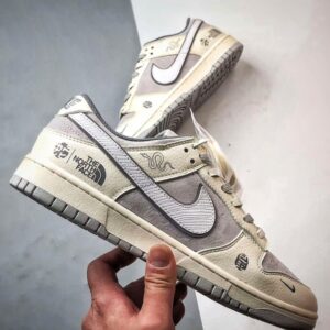 【AT3271】Nike x The North Faceのコラボレーションモデル、グレーと白の組み合わせのローカットシューズ、Nike Dunk Low RetroとThe North Faceのサイン入り。シューズは、ホワイトとグレーの配色で、北面のシンボルがデザインされています。パッと目を引くスタイリッシュなランニングシューズです。